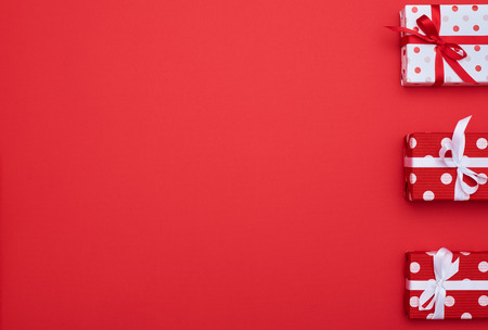 High angle of gift boxes trio with copy space over red flat lay backgroundの写真素材