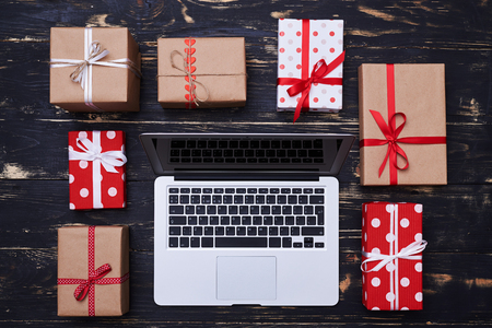 High angle of silver laptop encircled with many gift boxes isolated over gunge wooden flat lay backgroundの写真素材