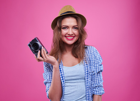 Close-up of smiling girl with a retro camera in hands posing at the camera.の写真素材