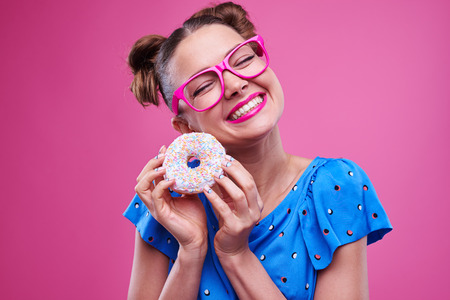 Close-up of exhilarated smiling woman with sprinkled donut.の写真素材