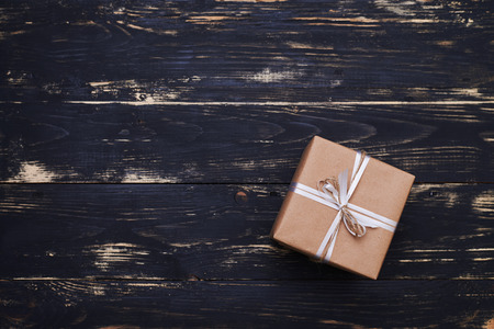 High angle of square box tied with silver ribbon. Light brown wrapping paper isolated on the flat layoutの写真素材