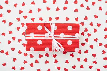High angle of red dotted gift box with white ribbon.
