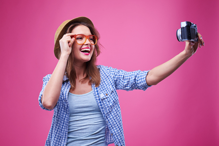 Mid shot of funny youth wearing orange glasses and making a selfie photo with one hand.の写真素材