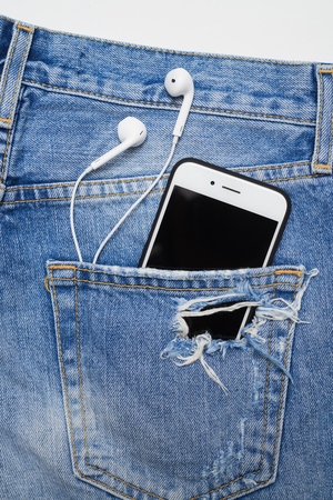 Top view of a cellphone with headphones in the pocket of ripped denim shorts. Summer vacation itemsの写真素材