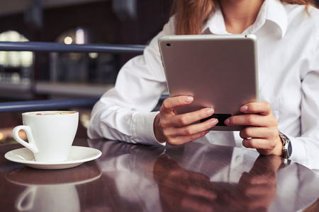Cropped shot of slim pretty girl having rest on lich with cup of coffee while working with tabletの写真素材