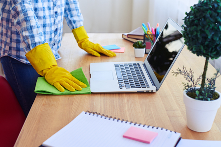 Cropped shot of woman dusting desk and laptopの写真素材
