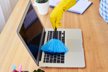 Cropped shot of charwoman dusting with small broom keyboardの写真素材