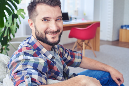 Close-up of handsome man with blue eyes relaxing on fashionable sofaの写真素材