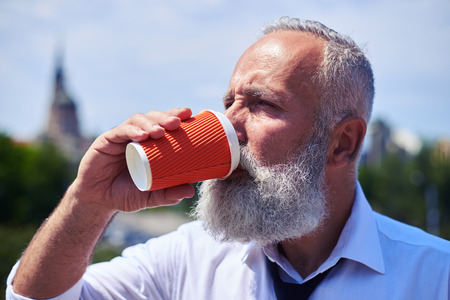 Close-up of concentrated male drinking coffee and enjoying panorama of cityの写真素材