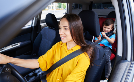 Wide shot of female driving car with son sitting in baby seatの写真素材