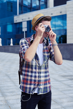 Outdoors shot of stylish handsome man with vintage camera taking photos in downtownの写真素材