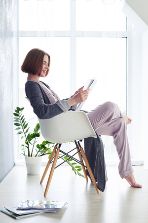 Vertical of madam reading magazine on armchair with copy spaceの写真素材