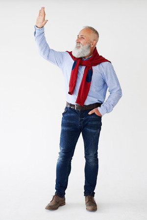 Full-length shot of smiling senior bearded man waving for someone on sidewayの写真素材