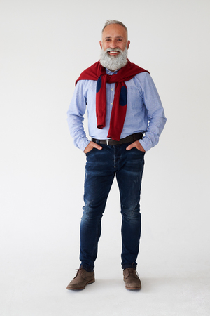 Full-length shot of casual mature bearded man posing with hands in pocket, isolated on white backgroundの写真素材