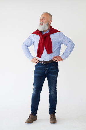 Fill-length shot of positive bearded mature man holding hands on waist, looking sidewardの写真素材