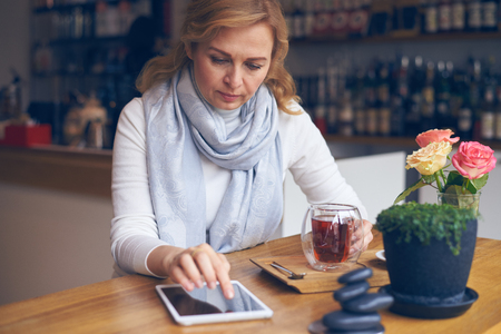 Closeup of thoughtful mature woman using tablet with black screenの写真素材