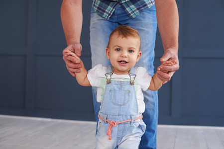Closeup of cute little daughter holding hands of father while doing steps の写真素材
