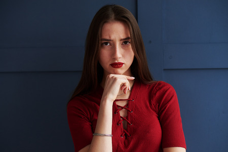 Portrait of serious girl with red lips posing against background の写真素材