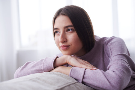 Closeup of dreamy girl relaxing on sofa at homeの写真素材