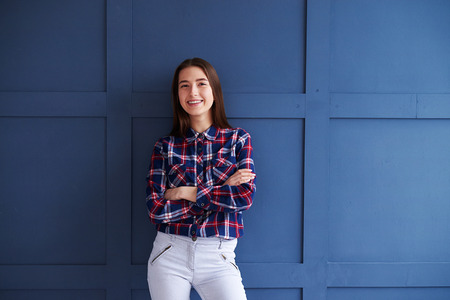 Portrait of smiling girl in casual clothing standing against background and looking at cameraの写真素材