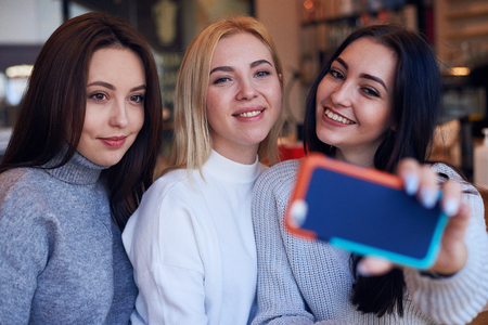 Closeup of three women making selfie at cafeの写真素材