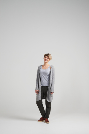 Full-length shot of attractive woman wearing cardigan posing at studioの写真素材