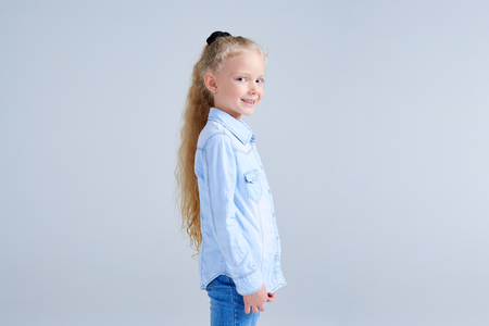 Side view of pretty girl with blonde hair in ponytail looking at cameraの写真素材