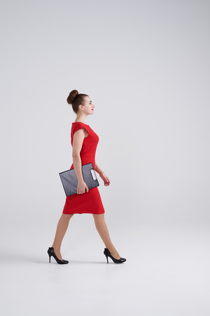 Side view of concentrated businesswoman walking and holding folder in handsの写真素材