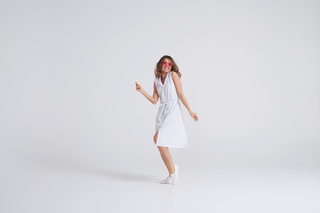 Indoor portrait of charming young woman in dress having fun at studioの写真素材