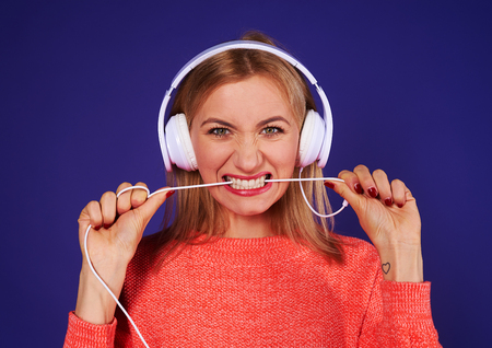 angry blond in headphones biting cordの写真素材
