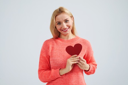 smiley blond holding small red heartの写真素材