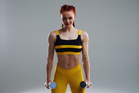 rude sportswoman standing with dumbbellsの写真素材