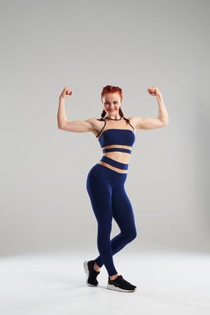 sportswoman in blue sportswear showing bicepsの写真素材