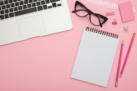 Beautiful flatlay with laptop, glasses and stationery on pink deの写真素材