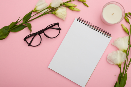 Workspace table with glasses, notebook, flowers and candles on pの写真素材