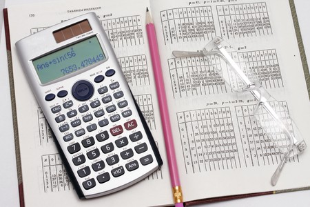 The calculator the pencil and points lie on the table with the dataの写真素材