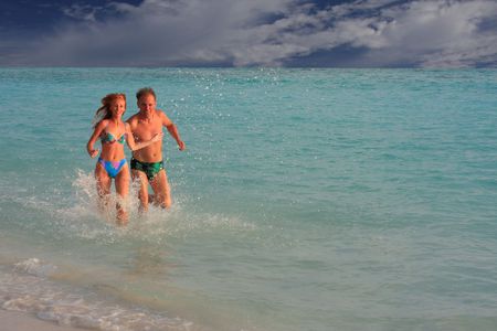 Men and woman runs along ocean coast on waterの写真素材