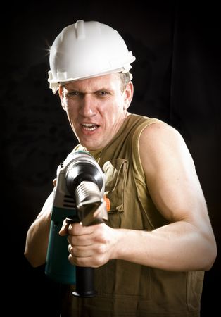 The builder in a protective helmet holds the professional puncher-hammer with a drill of the big diameter の写真素材
