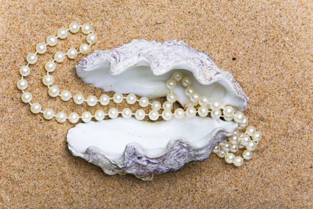 The shell with a pearl beads lies on sand の写真素材