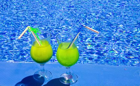 Glasses  with cocktail on edge of poolの写真素材