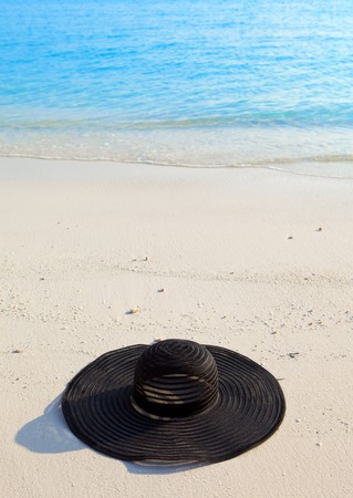 Black millinery  from sun ays on sand before oceanの写真素材