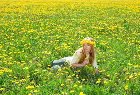 Young pretty woman in wreath of dandelions in the meadow solar dayの写真素材