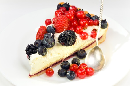 Piece of a pie with fresh berries on a plate and with a silver spoonの写真素材