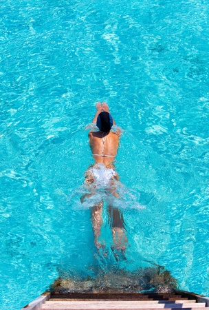 Maldives. 
Young sports woman swims from steps of villa on water.

の写真素材