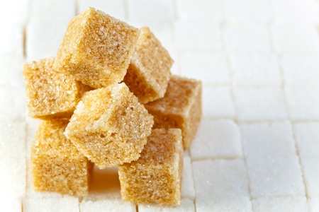 Cubes of not refined reed sugar lie on pieces of white sugarの写真素材