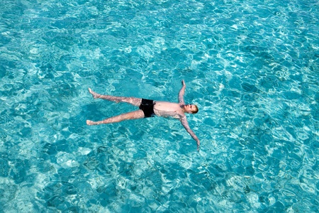 Teenager has a rest on turquoise transparent water of ocean