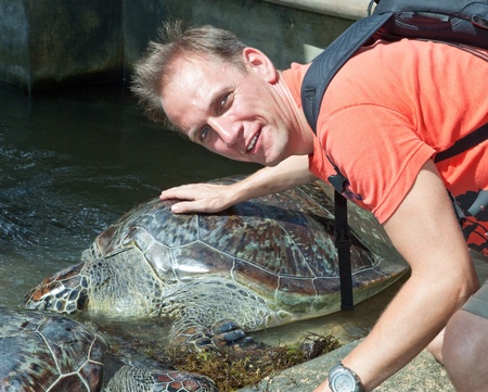 The man strokes an armor of a large turtle