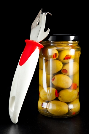 Glass jar with tinned olives  and a can openerの写真素材