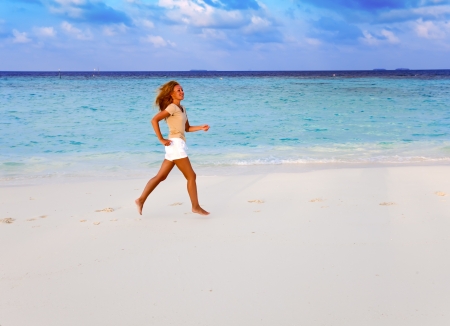 The sporting woman runs on the seashore. Maldivesの写真素材