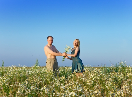 The happy young pair in the field of chamomiles の写真素材